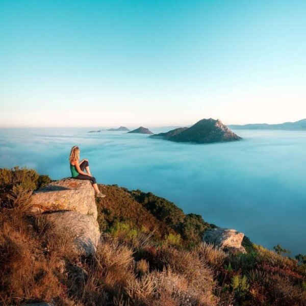 woman sitting on a hill overlooking a scenic view